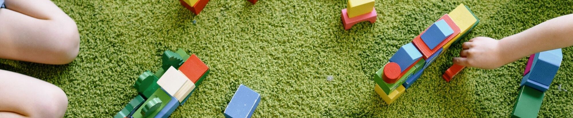 Kinder mit Spielzeug auf einem Teppich