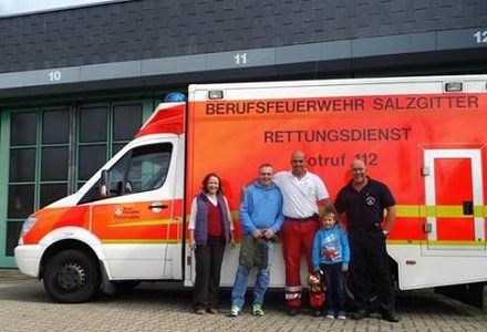 Jannik mit seinen Eltern und Mitarbeitern der Feuerwehr vor einem Rettungswagen.