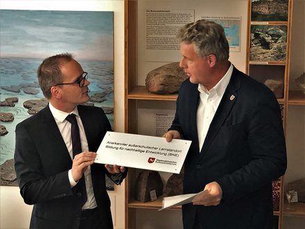 Kultusminister Grant Hendrik Tonne überreichte Salzgitters Kulturdezernent Jan Erik Bohling die Tafel, die am Städtischen Museum auf den Außerschulischen Lernort hinweisen wird.