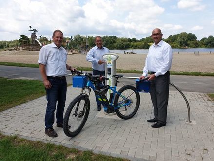 Torsten Fleige-Lütgering, Matthias Giffhorn und Rainer Krause präsentieren die E-Bike-Ladestation am Salzgittersee.