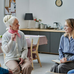 Das Bild zeigt eine Seniorin und einen Senior im Gespräch mit einer jungen Frau.