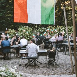 Menschen sitzen an Tischen im Biergarten des Peak-Hotels bei einem italienischen Abend