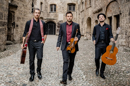 Die drei Musik von Cobario auf einer Treppe mit ihren Musikinstrumenten.