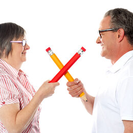 Smiling couple holding big pencils